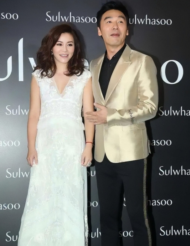 钟镇涛携小12岁妻子范姜出席活动的照片。镜头下的钟镇涛身穿金色西装搭配黑色裤子，