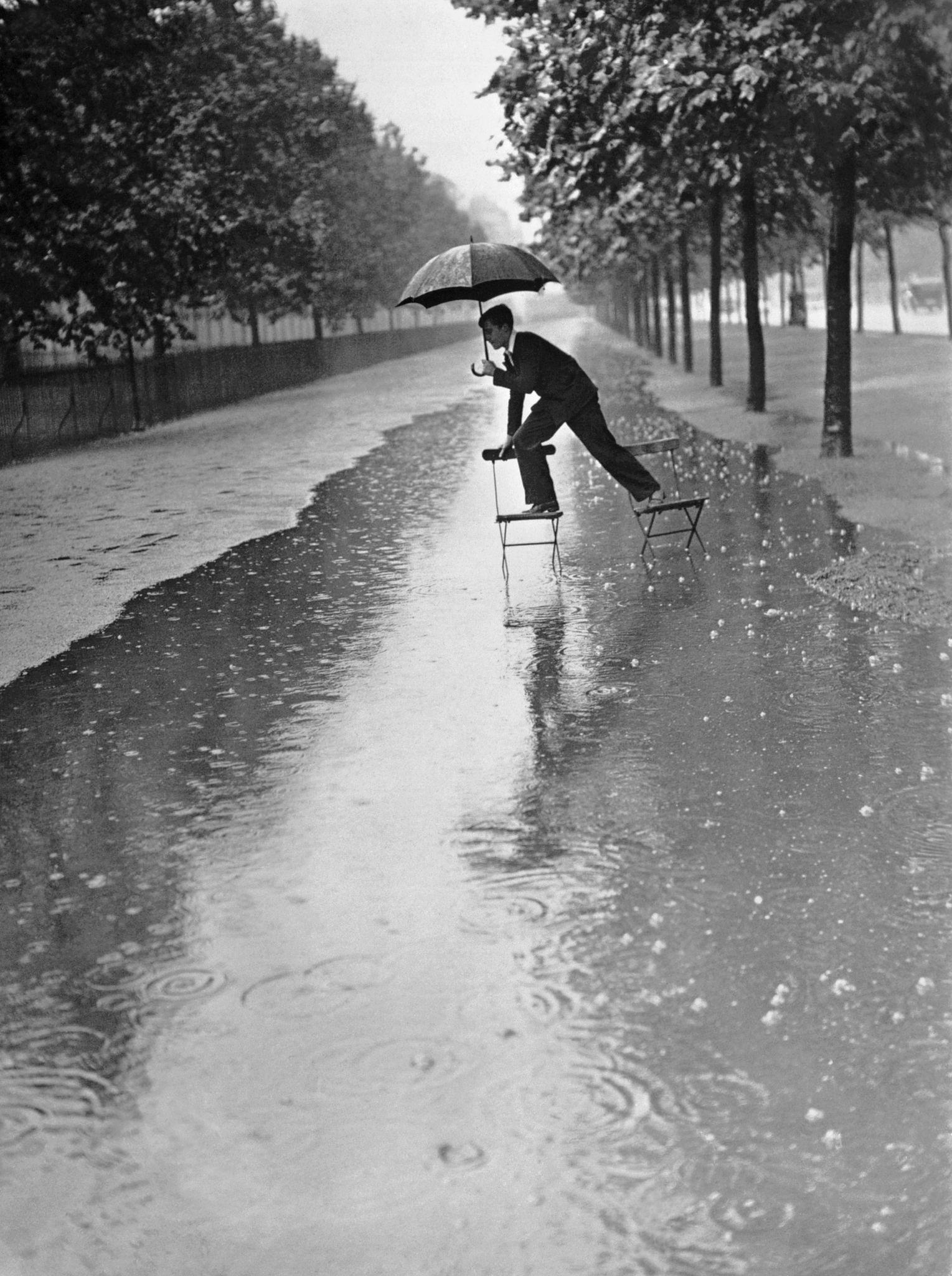 1934年，大雨中，一名男子踩过伦敦的一个大水坑。