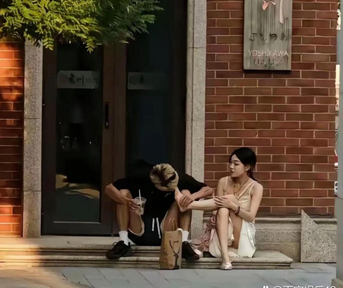 街头一隅，一对情侣映入眼帘。许是逛累了，两人就地歇脚。男孩满眼宠溺，轻柔为女孩按