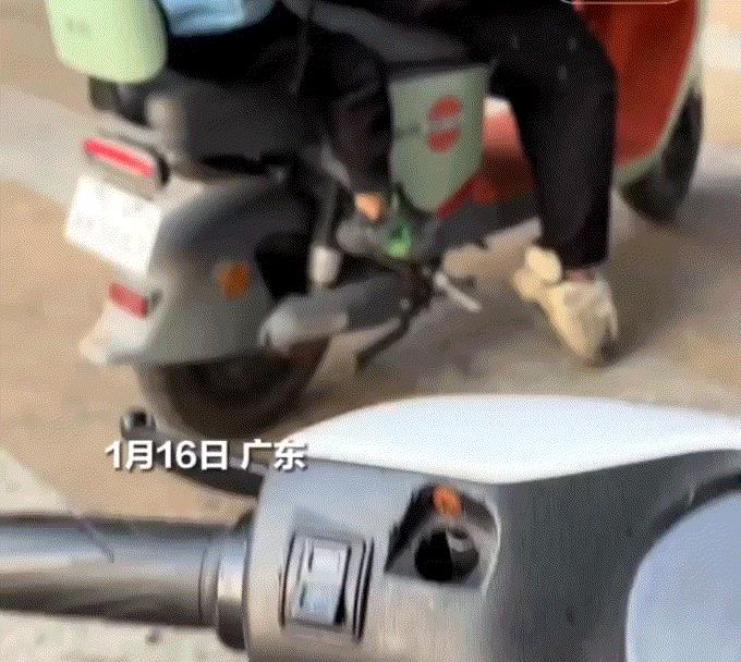 广东，一妈妈驾驶电动车拉着孩子行驶在路上，结果在等红绿灯通行之时，孩子竟拿着一把