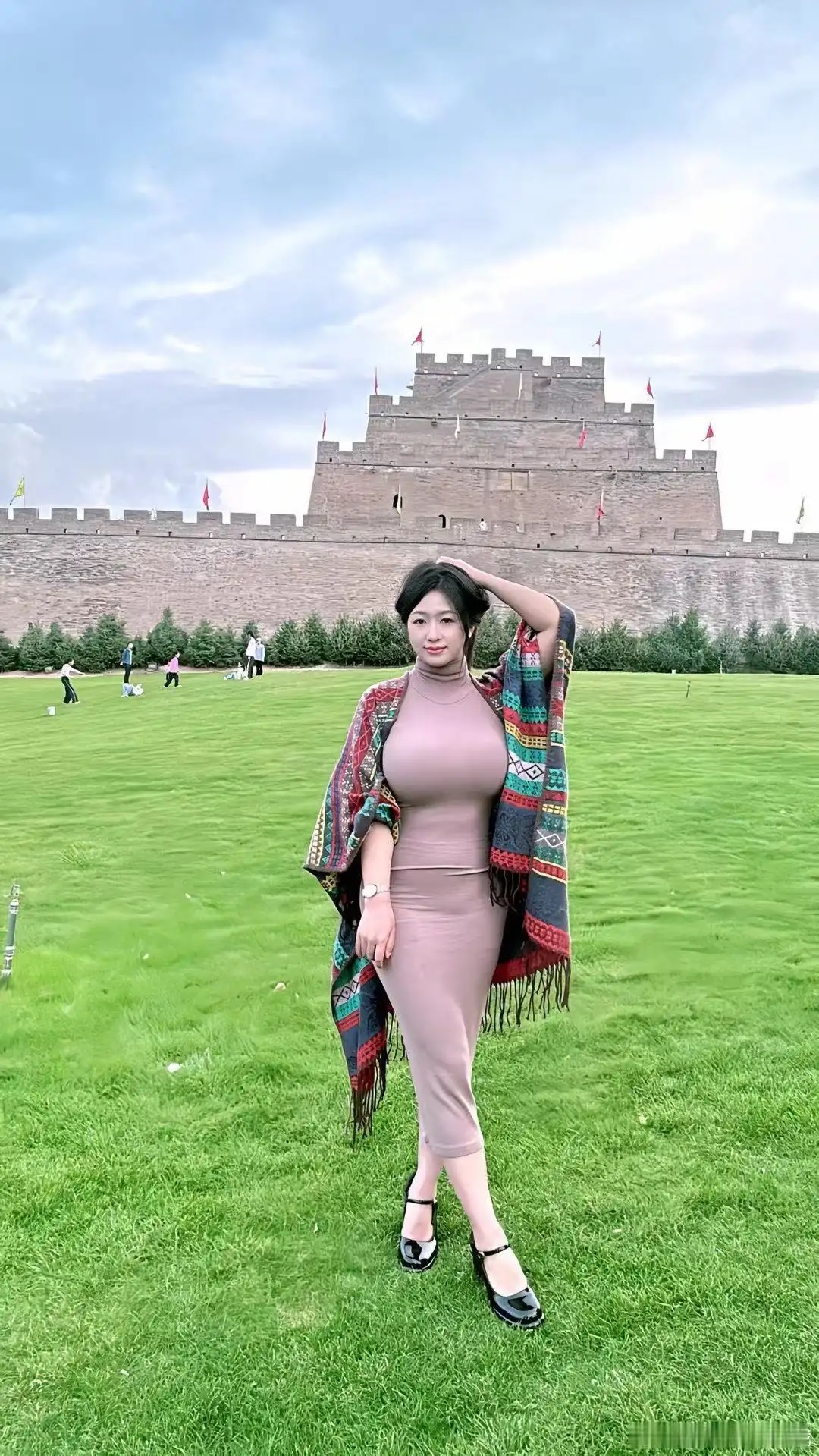 浅粉裙搭彩披肩，古城前展时尚风采。