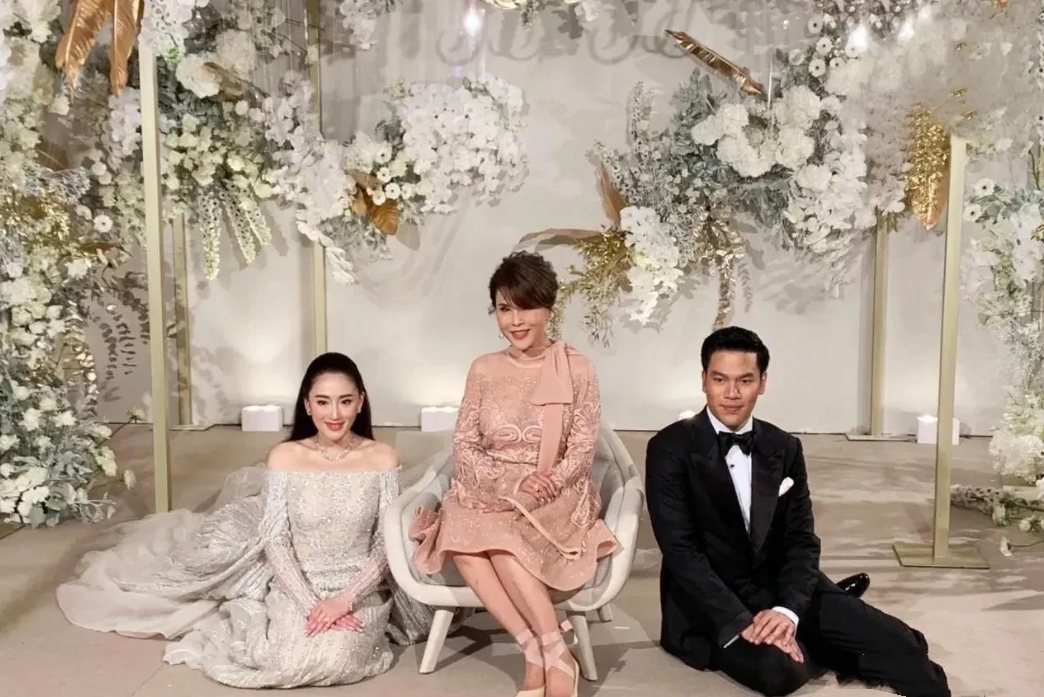 这是泰国现任总理佩通坦结婚时的照片，新婚夫妇坐在地毯上，中间坐在沙发上的女士你知道是谁吗？