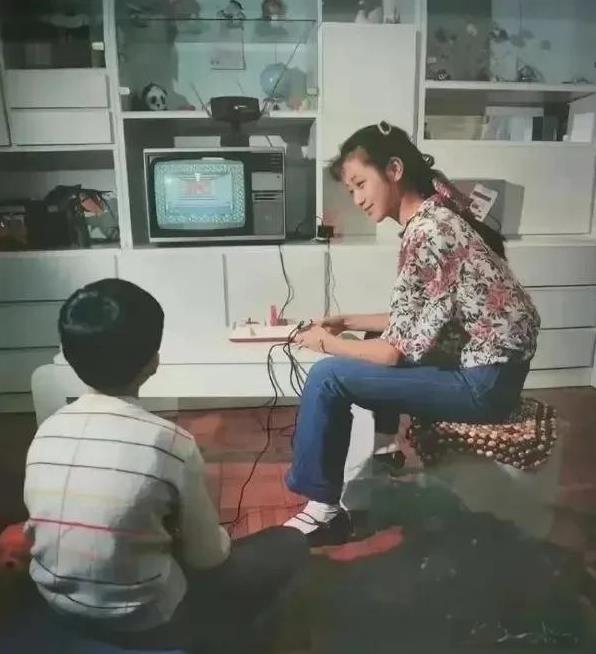 这是拍摄于1988年的一张照片 ，男孩女孩正在玩游戏机，电视虽然不大，但是彩色的