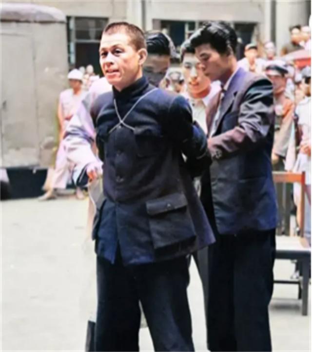 1949年3月27日，上海街头，一名身穿蓝色衣服的中年男子被押送下车。周围群众围