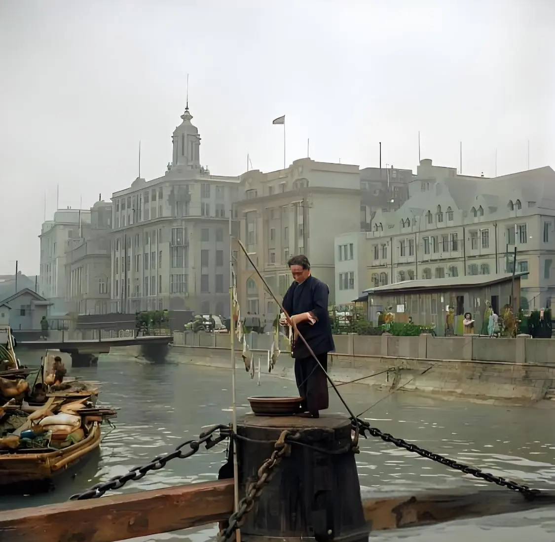 1940年上海外滩，黄浦江浮动码头的固定桩上晾晒渔获的中年妇女。