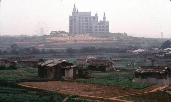 这是90年代深圳城乡结合部的一处农房，照片中，远处的摩天轮、高楼和近处破旧的房屋