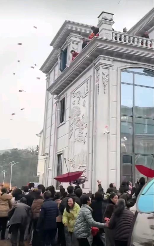 1月25日，江西上饶，一户人家为庆祝新屋落成，一家人豪横地从楼上给楼下围观的邻居