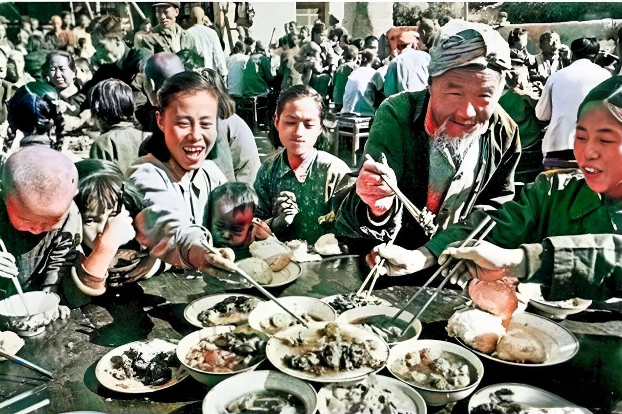 1958年，人民公社社员热热闹闹地聚在一起吃“大锅饭”。老人、孩子、妇女的脸上露