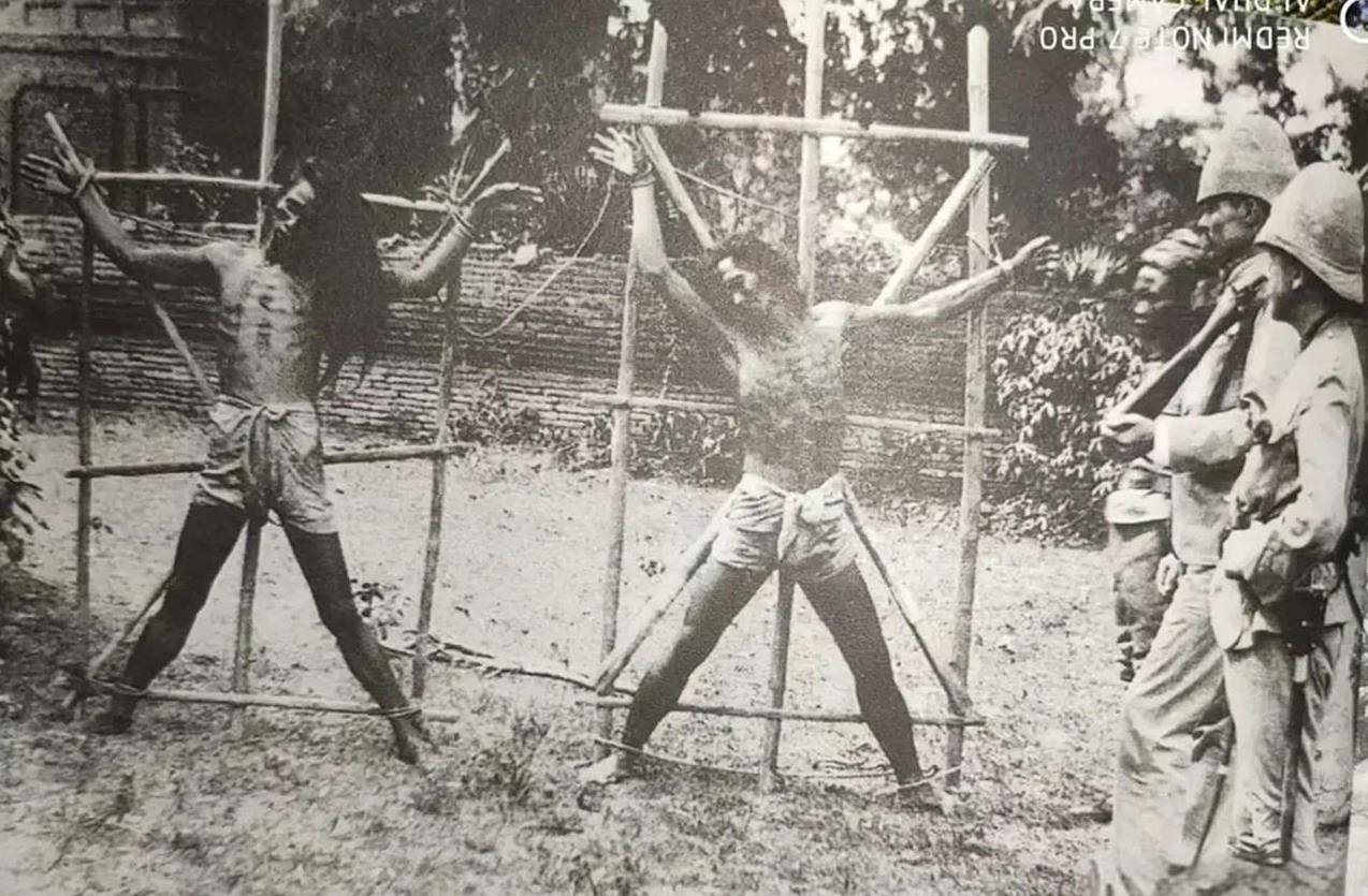 1889年，英国殖民者正在用“晒人干”的酷刑处死两个缅甸爱国者。他们四肢被绑在米