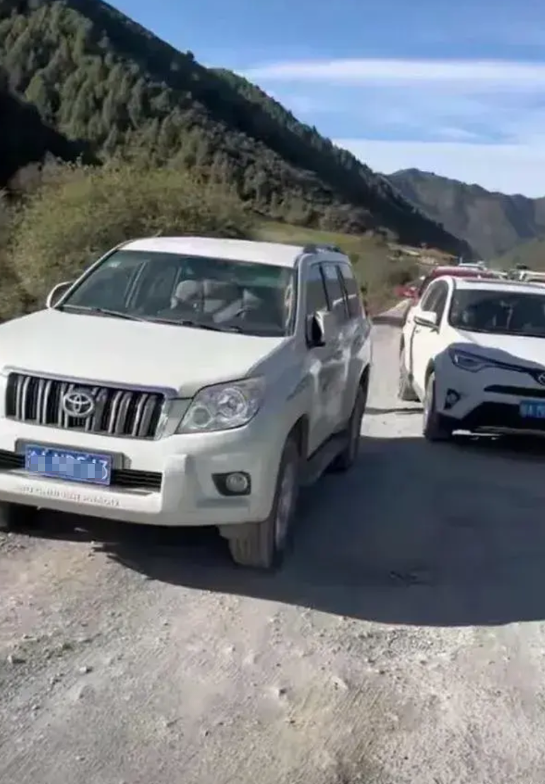 甘肃一对野游夫妻为了使旅游更加刺激，停车停在交通二行道上，以堵车取乐，自己则在旁