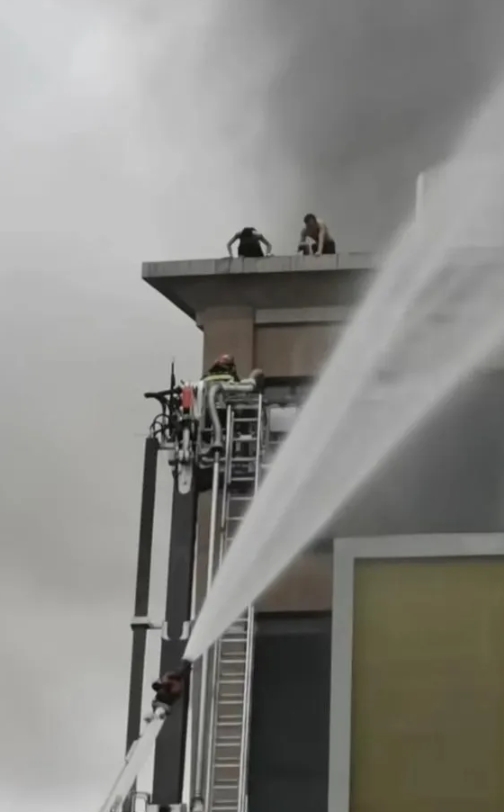 四川自贡市百货大楼发生火灾，火势严重，图中的两个小伙爬上楼顶呼救，随着火势越来越