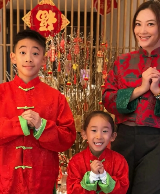 照片中，应采儿身穿红绿相间新中式上衣搭配黑色裤子，优雅气质，明艳动人。大儿子和小