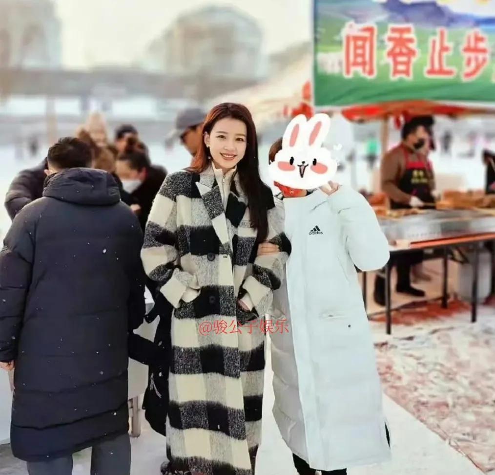 31岁的孙怡回到东北故乡欢度春节，身着黑白色格纹羊绒大衣逛集市，尽显亲民风范，在