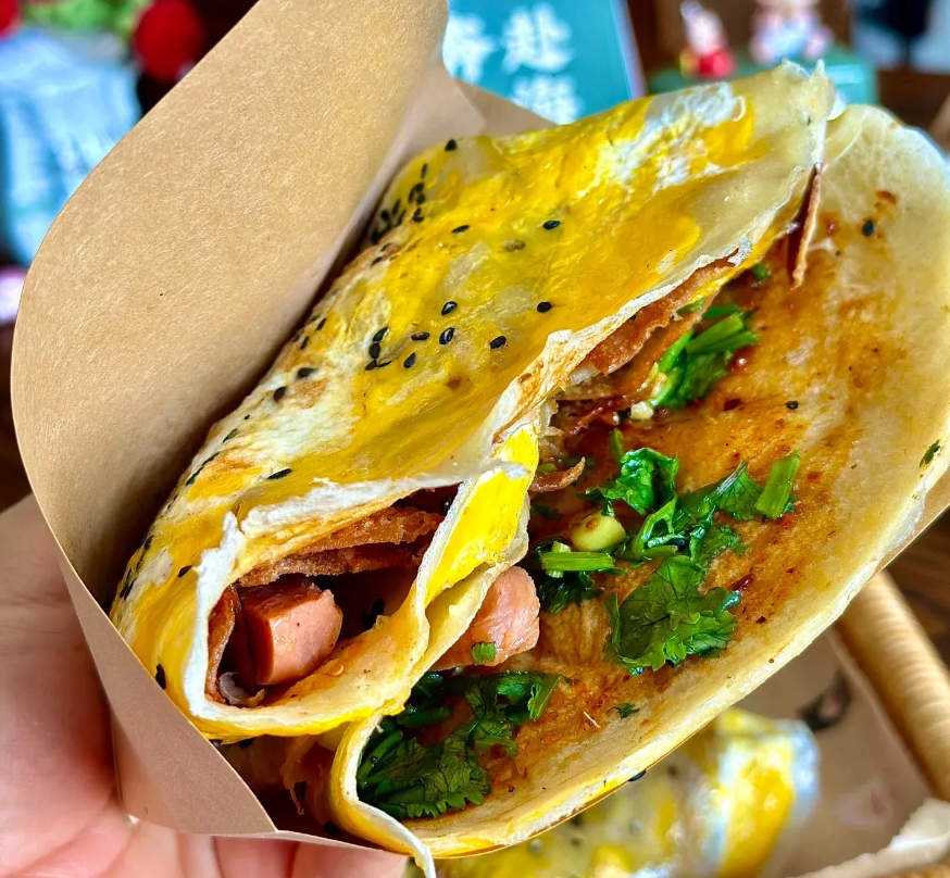 卖煎饼果子能月入上万吗？
孩子要吃煎饼果子。
我和孩子站在摊前等。
前面有2个人
