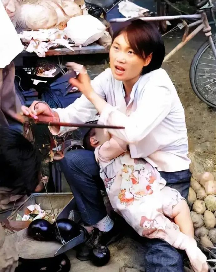 照片中的妈妈正在带着孩子卖菜