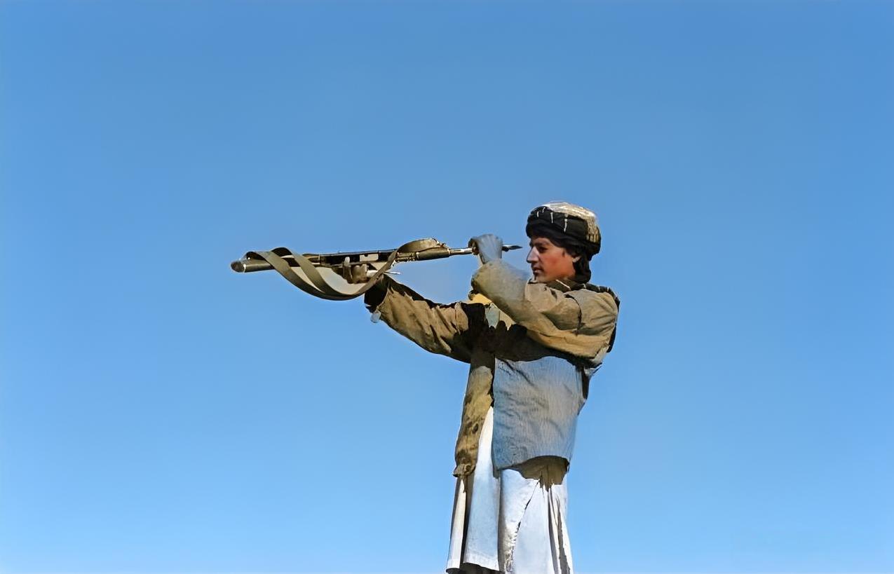 1996年，阿富汗一名塔利班武装战士正在检查他的AK47枪管。他用双手平抬起枪，