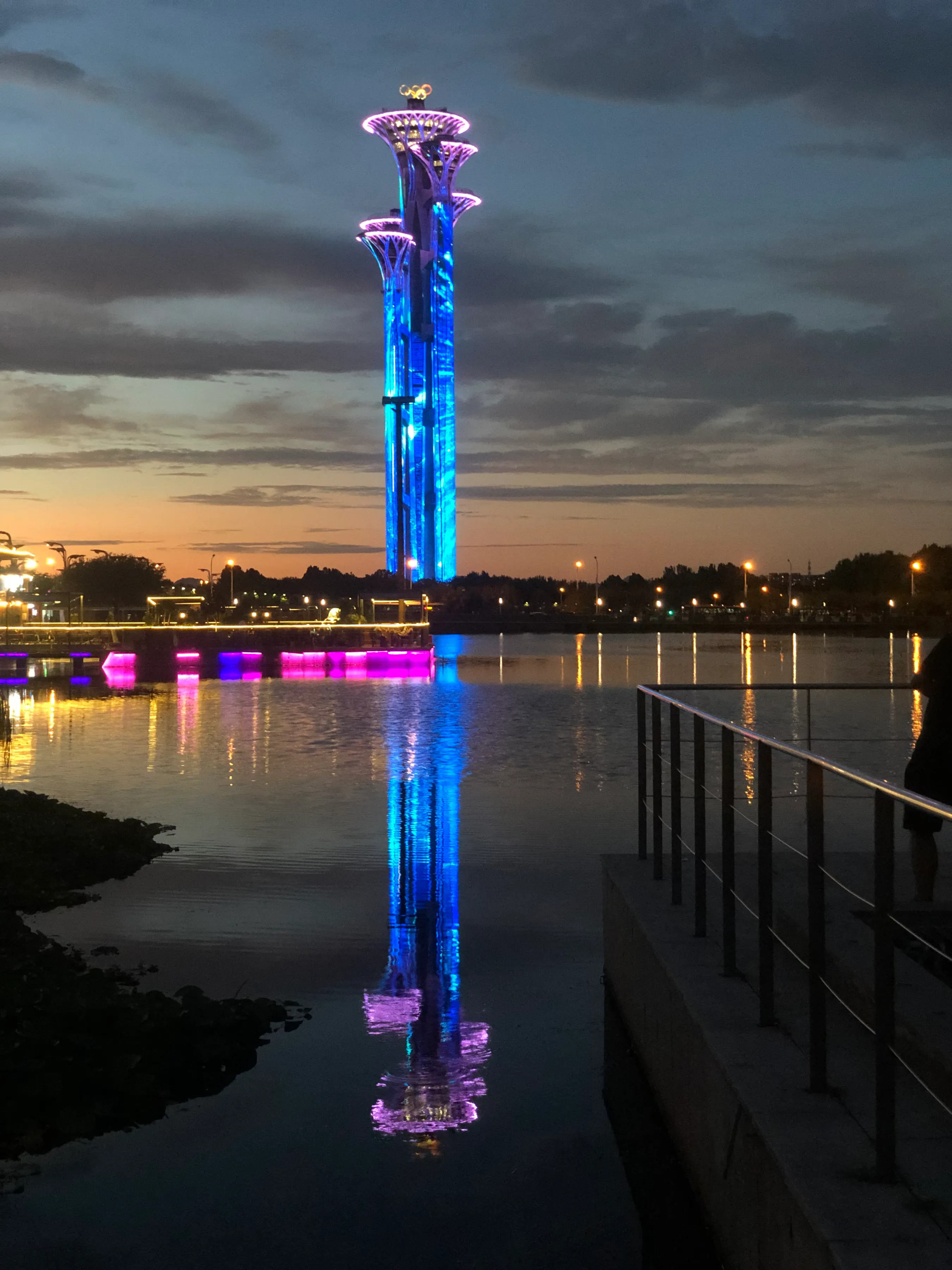 奥运五环塔经常换妆 , 徐徐晚风吹皱湖面 