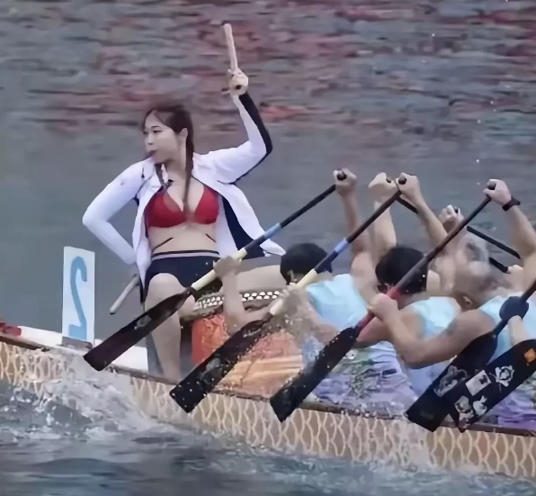 这个龙舟队有高招，搞个漂亮的少妇当鼓手，披巾露胸，穿个裤衩，双腿分开，这就是所谓