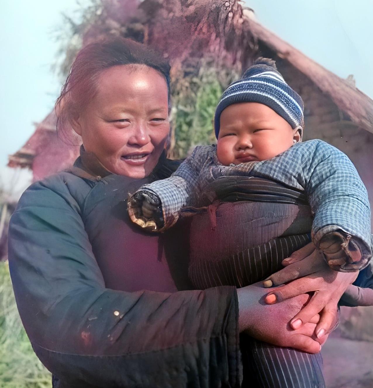 民国，一位虎背熊腰的母亲抱着他的胖儿子。这位母亲一脸男相，一双手也像男人的手一般