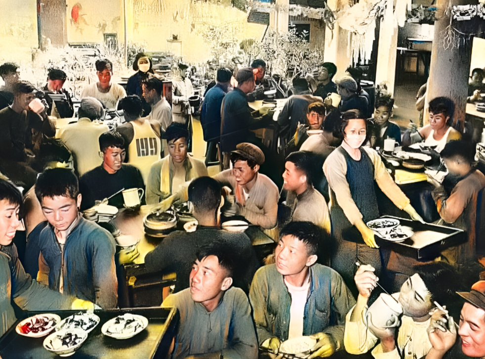 1958年，人民公社的大食堂里热闹非凡。每一张饭桌旁都坐满了社员。每一名社员的脸