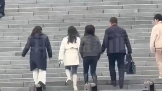 杨妞花和姐姐手拉手走进法院，听到粉丝喊妞花，姐妹俩鞠躬感谢。