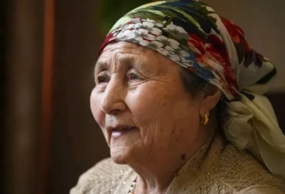 1977年，新疆的冬天，一个戴着破旧帽子的11岁汉族女孩，正在垃圾桶旁翻找可以充