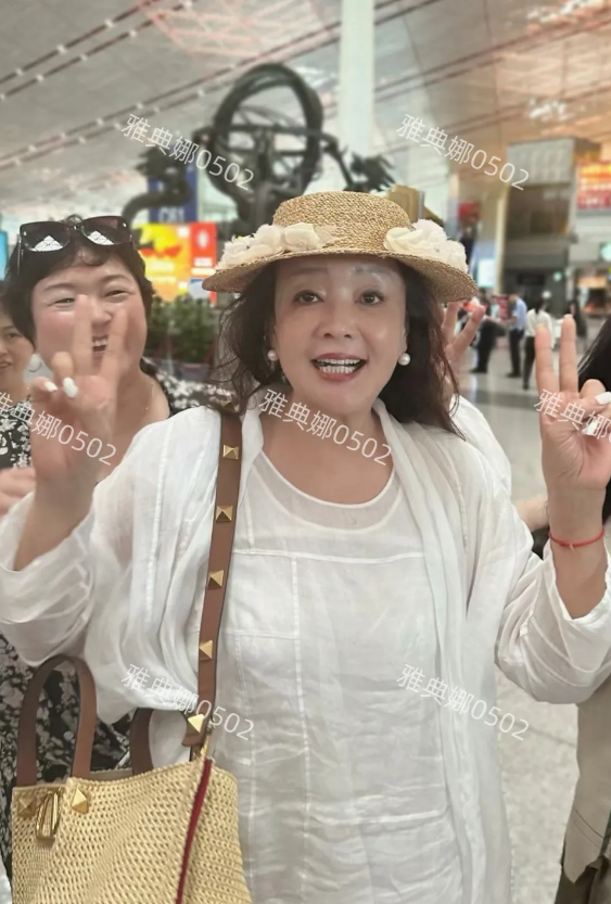 北京机场偶遇张兰，66岁的她面色红润精气神很足，穿着白色连衣裙戴着法式花朵草帽特