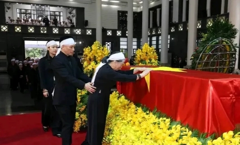 这是越南阮富仲逝世后其家属在悼念现场走过灵柩的现场画面，画面中阮夫人双手轻轻抚摸