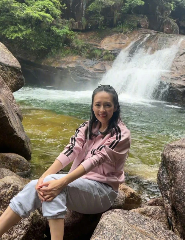 章子怡时隔25年重返电影《卧虎藏龙》的拍摄地，章子怡面带微笑的坐在瀑布前，一点儿