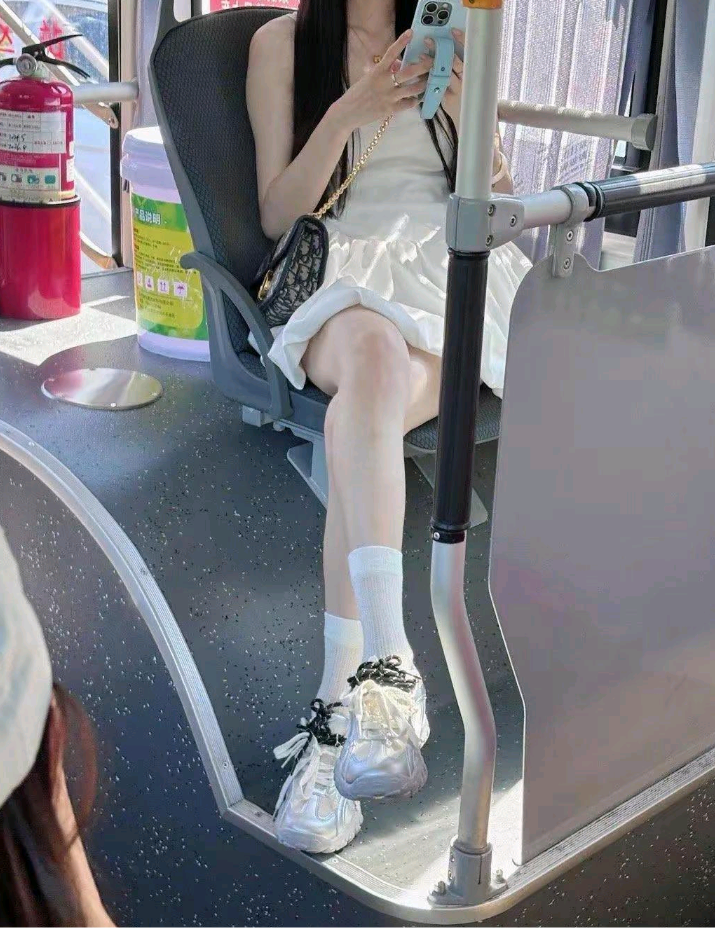 在公交车上捕捉到一位优雅的女士，她全神贯注地看着手机，对周围的世界浑然不觉。她那