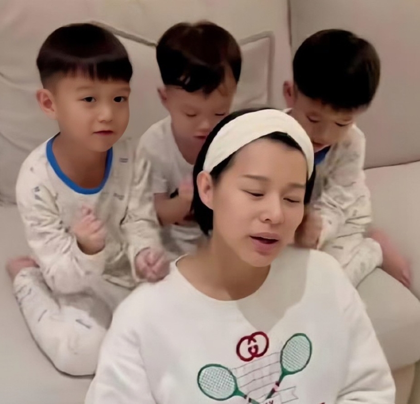 胡杏儿的三个儿子为她捶背的照片。镜头下的胡杏儿素颜出镜，身穿宽松的卫衣，靠着沙发