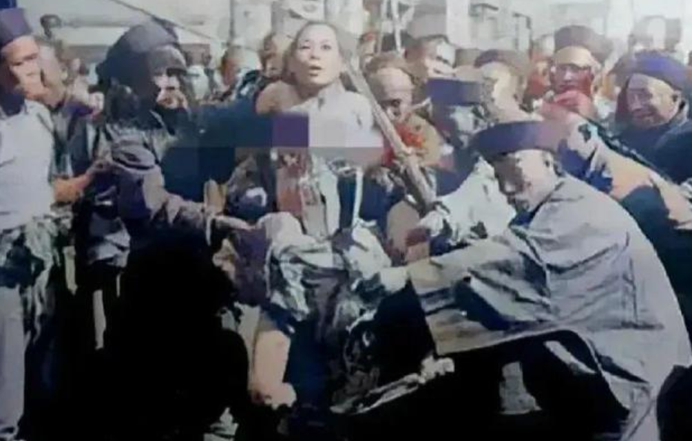 1905年光绪31年，一名女犯人被当众凌迟处死。一名手持大刀的刽子手已经将其大腿