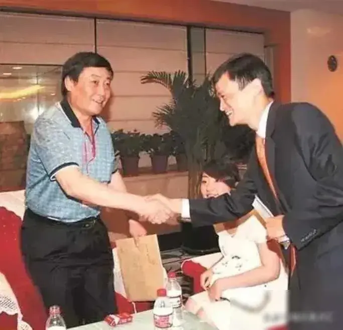 当宗庆后与马云握手时，桌子前摆放着一盒敞开的烟，而旁边则坐着宗馥莉，三人的体态对