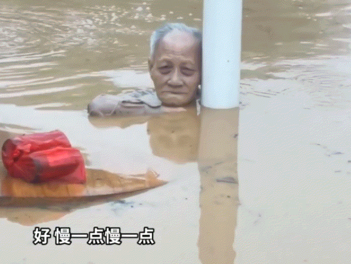 广东梅州的洪灾太可怕了。一位白发苍苍的老人被困在了洪水中，他安静的抱着一根电杆和