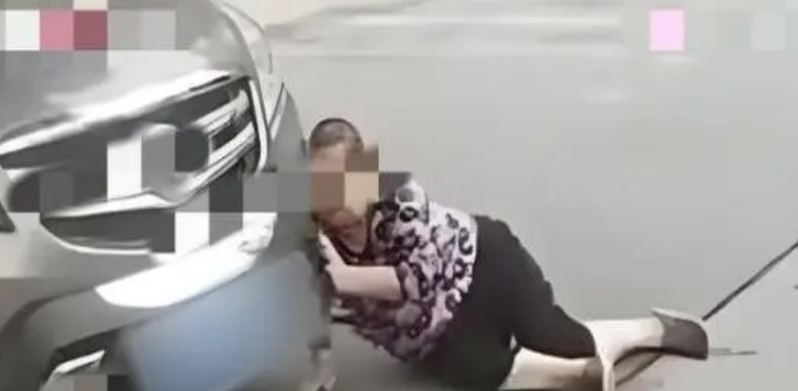 沈阳，大妈在路上看到停了一辆豪车，就往地上一躺想碰瓷儿，谁知车主因为堵车，干脆熄