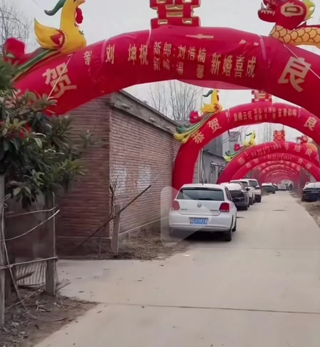 新农村结婚场地布置真是气派。几十面红旗路两旁迎风招展，接着是十个红色大拱门依次排