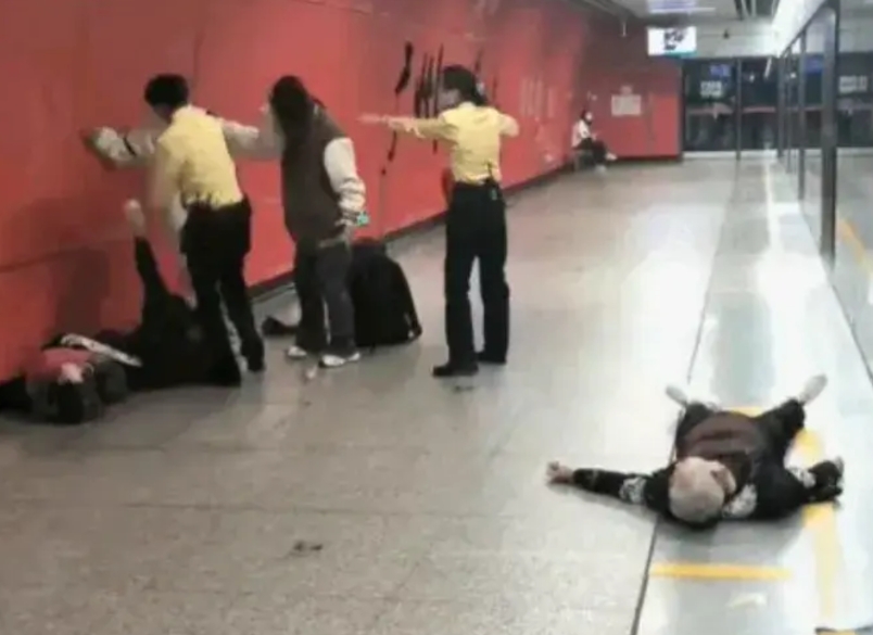 广州地铁站，一男一女两个年轻人殴打两位老人，其中一位老太太躺在地上。另一位在墙边