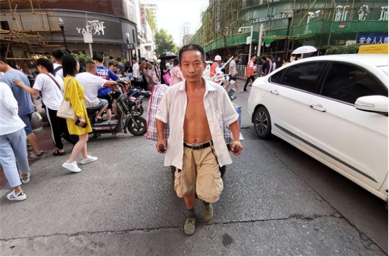 2019年，一个大叔拉着双轮拖车四处拾荒。当他走到在路口处时，一个红色的塑料袋引