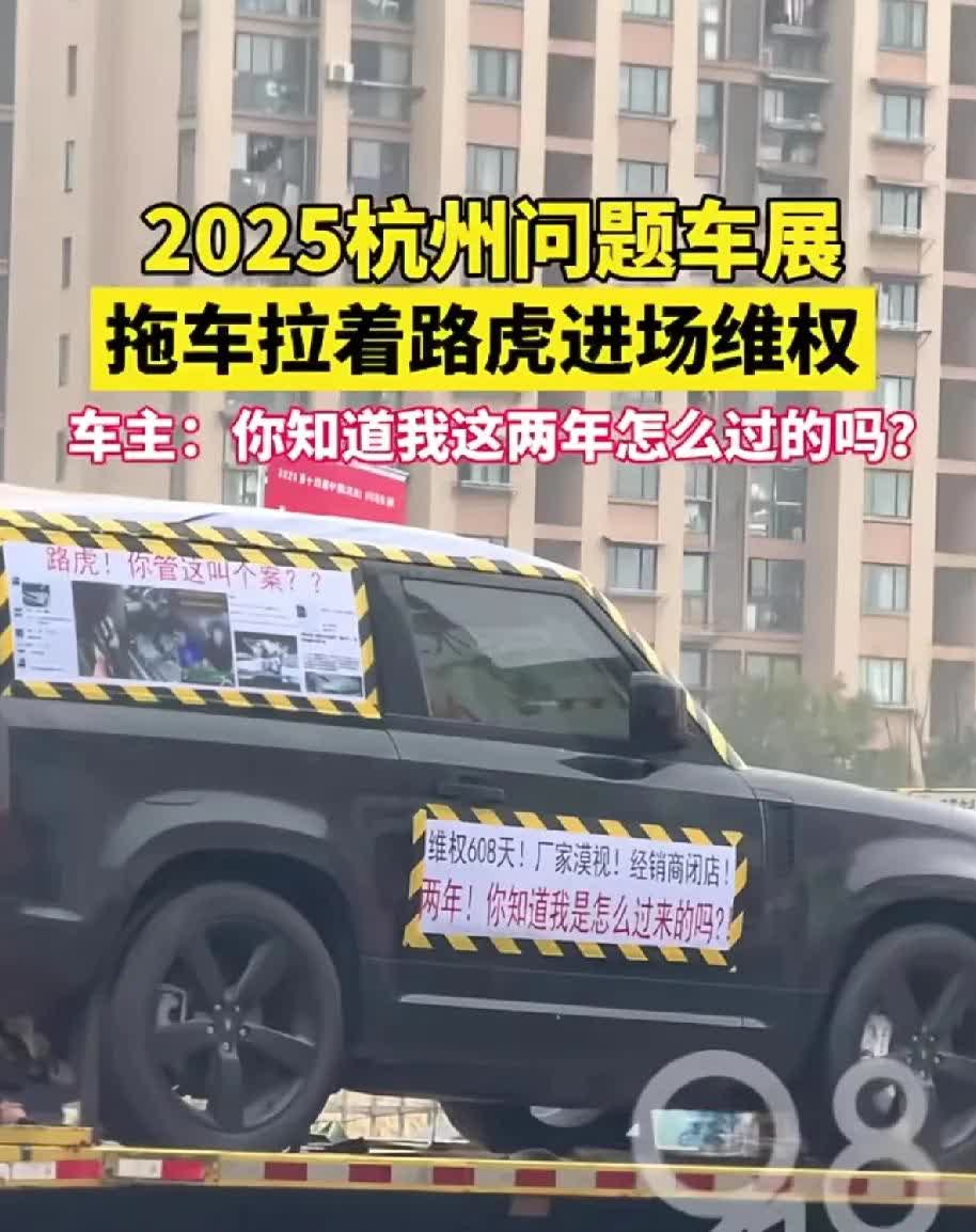 在今天的杭州问题车展上，一辆拖车拉着一辆进口路虎进场维权，车身上贴满了标语，“两