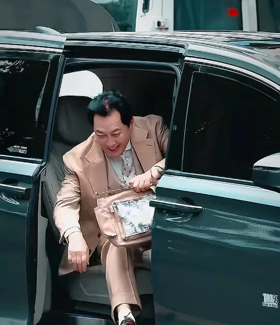 唐国强录制《王牌对王牌》，一身西服，背个妈咪包，里面装着的是他周边物料和一个红包