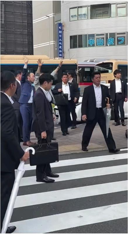 石破茂和保镖下属们过马路，斑马线两边道路上的汽车停止行驶，礼让一行人通过。
为了