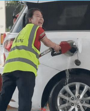 呀呀！这流淌的油算谁的啊！
一个加油站的工作人员正在为一辆车加油，当油加满后这支