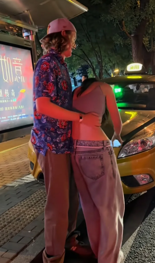 北京三里屯夜里灯火辉煌，一辆出租车停在马路边上等着一对情侣上车，男情侣是一名外国
