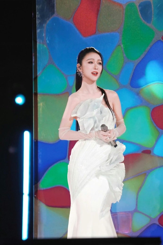 这身造型的精髓在于“若隐若现”的绿色薄纱，它为纯净的白色增添了灵动的层次感，如同