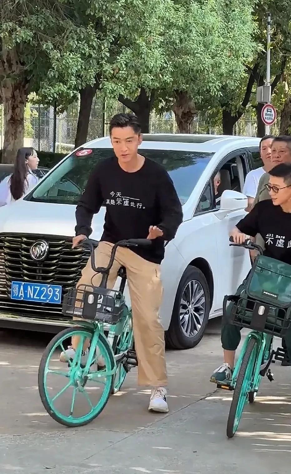 胡歌在街头骑单车，街边挤满了围观的群众