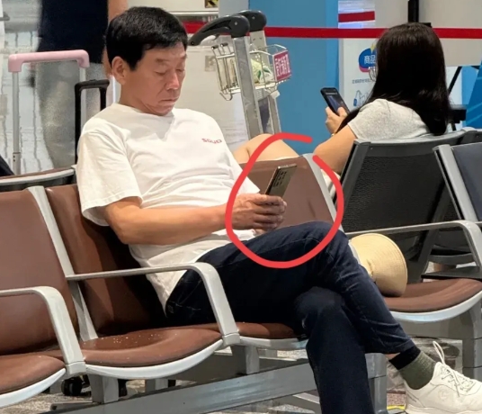 网友拍到魏建军在凳子上坐着休息看手机。
手机牌子看不出来，从摄像头分布看，是国产