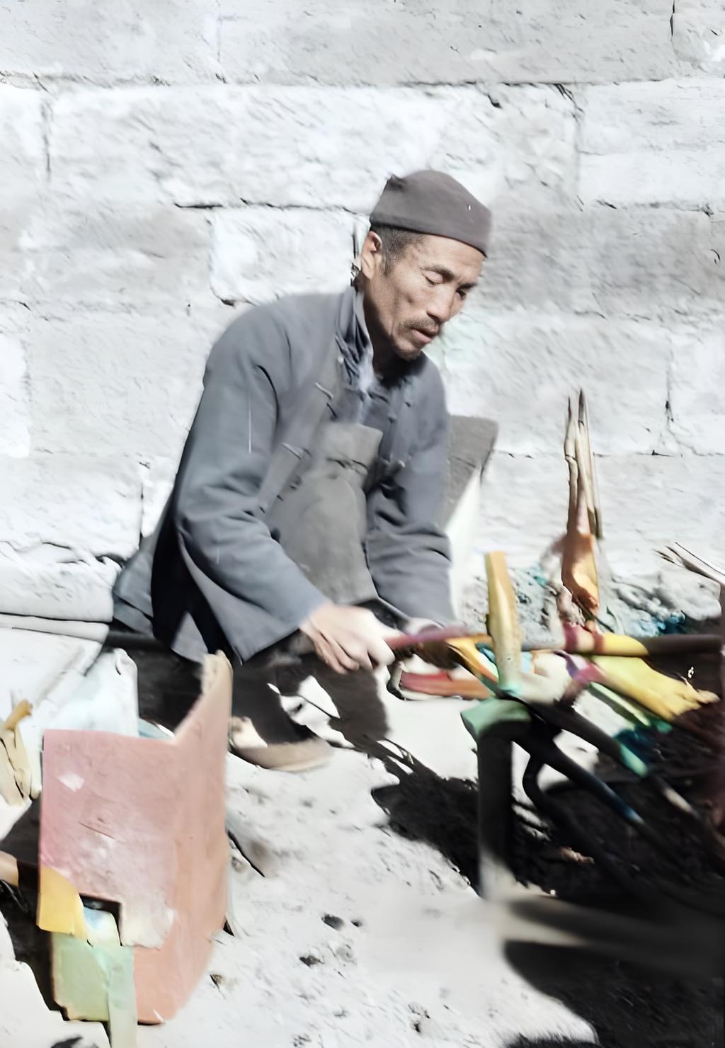 这是一位传统铁匠在进行打铁作业的场景。画面中人物身着旧式衣物，专注于手中铁器加工