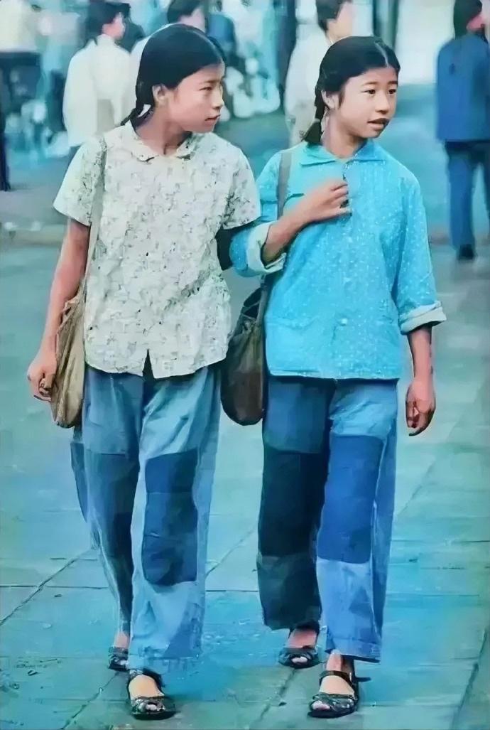 这是70年代初，穿着“补丁”衣服的两个女孩，昂首阔步的走在大街上，照片中她们的膝