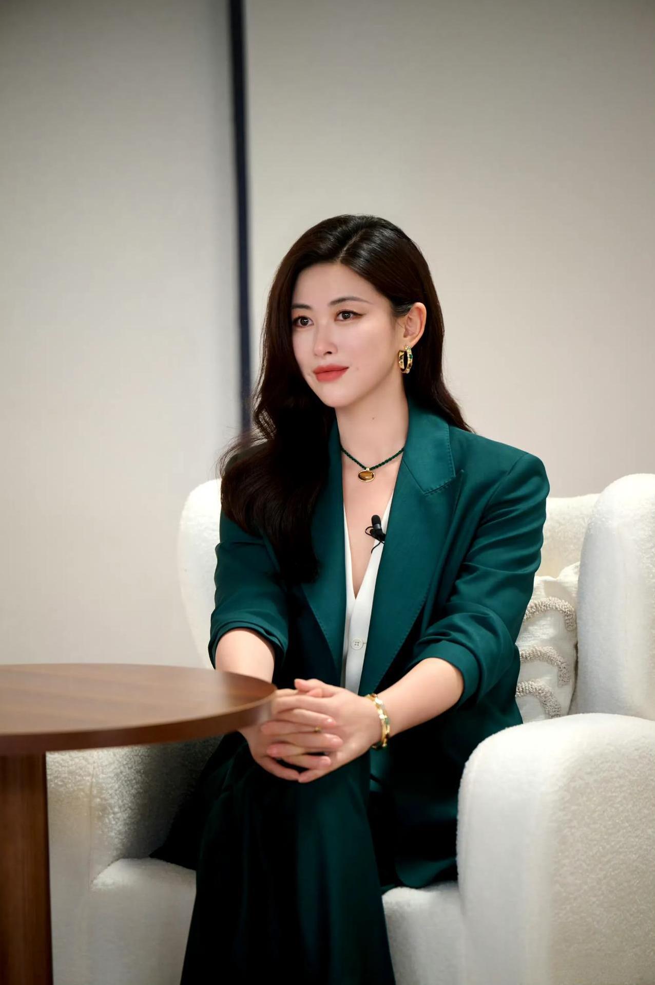 墨绿西装裁出飒爽轮廓，白缎内搭晕染隐性感，金饰与绿宝石串联起精致细节。静坐时藏起
