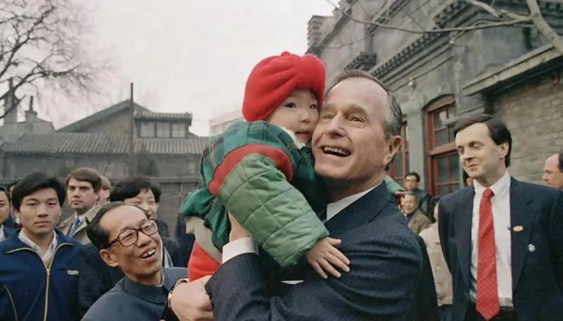1989年2月26日，时任美国总统老布什访问中国。怀中抱着一个小朋友，愉快合影。